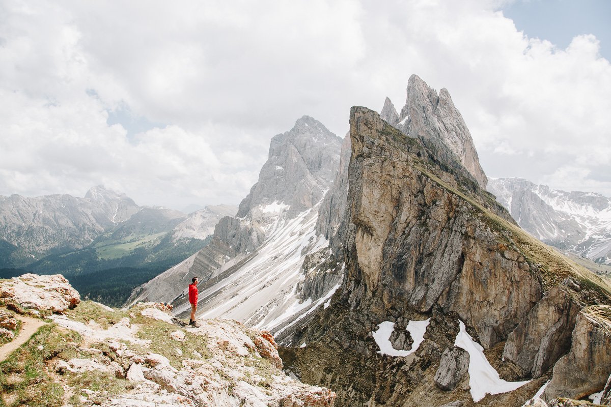 el hombre se encuentra frente a los picos irregulares dramáticos en los Dolomitas