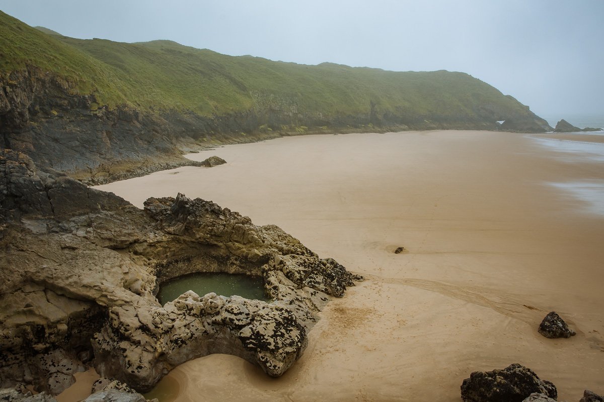 piscina de roca circular en una amplia playa de arena