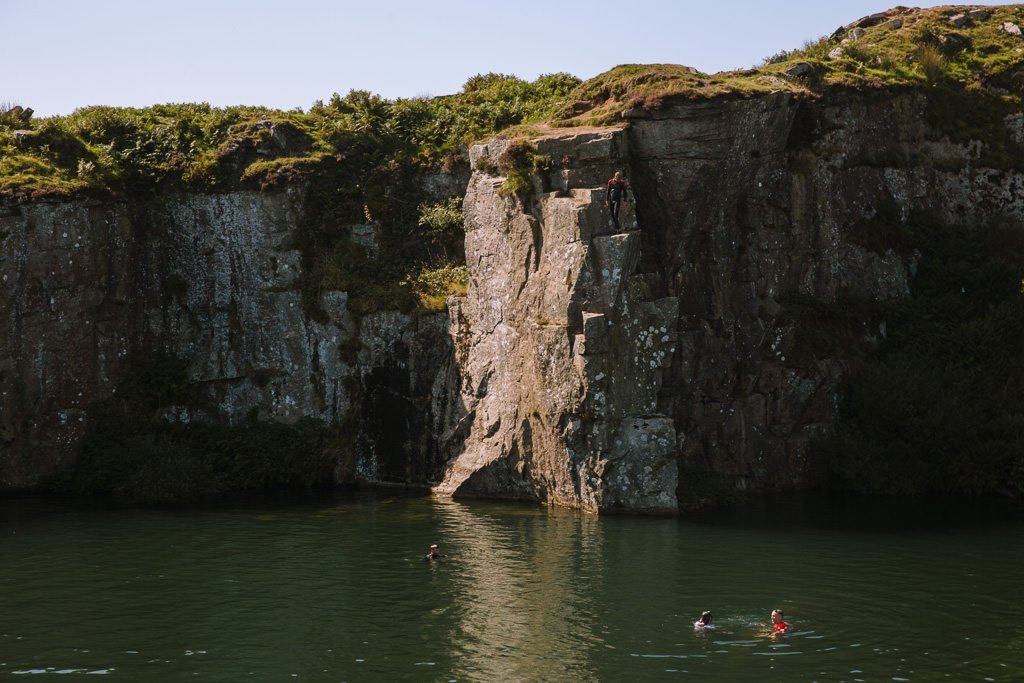 Los lados rocosos empinados de una antigua cantera con personas nadando en la piscina en la parte inferior