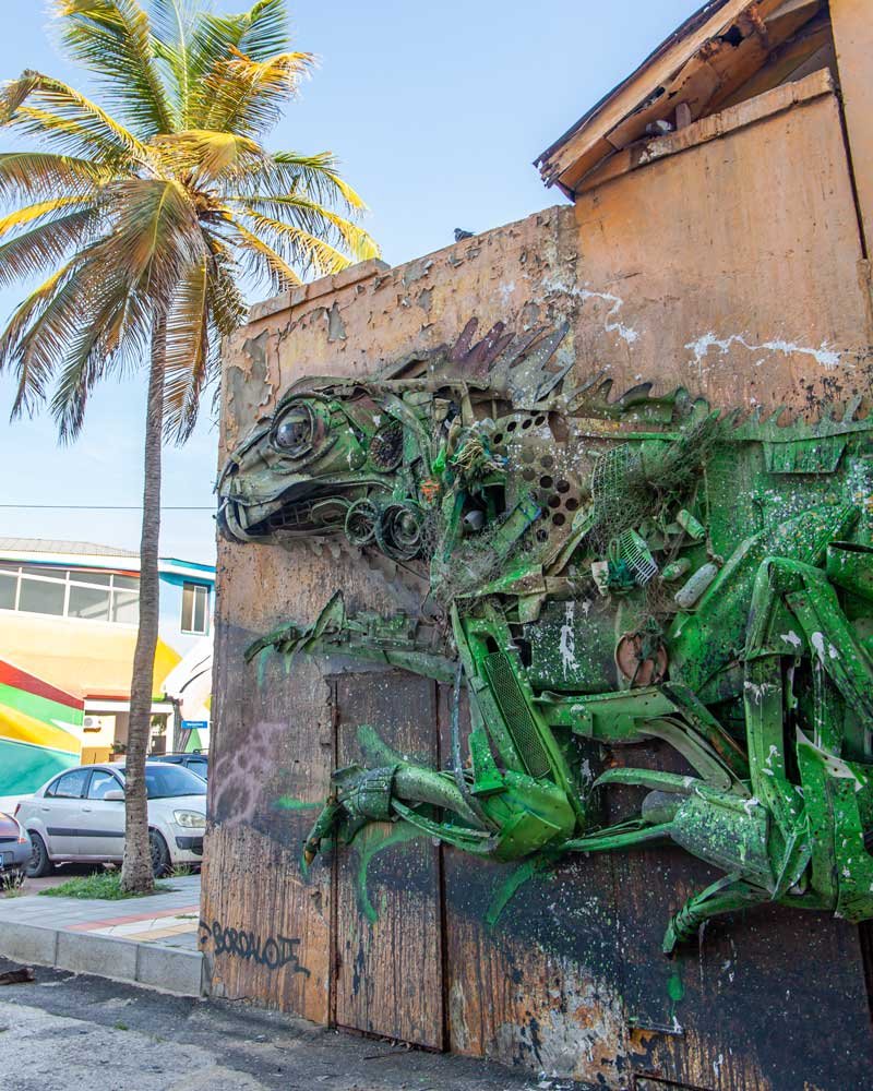 Arte callejero de una iguana verde hecha de materiales reciclados en San Nicolás