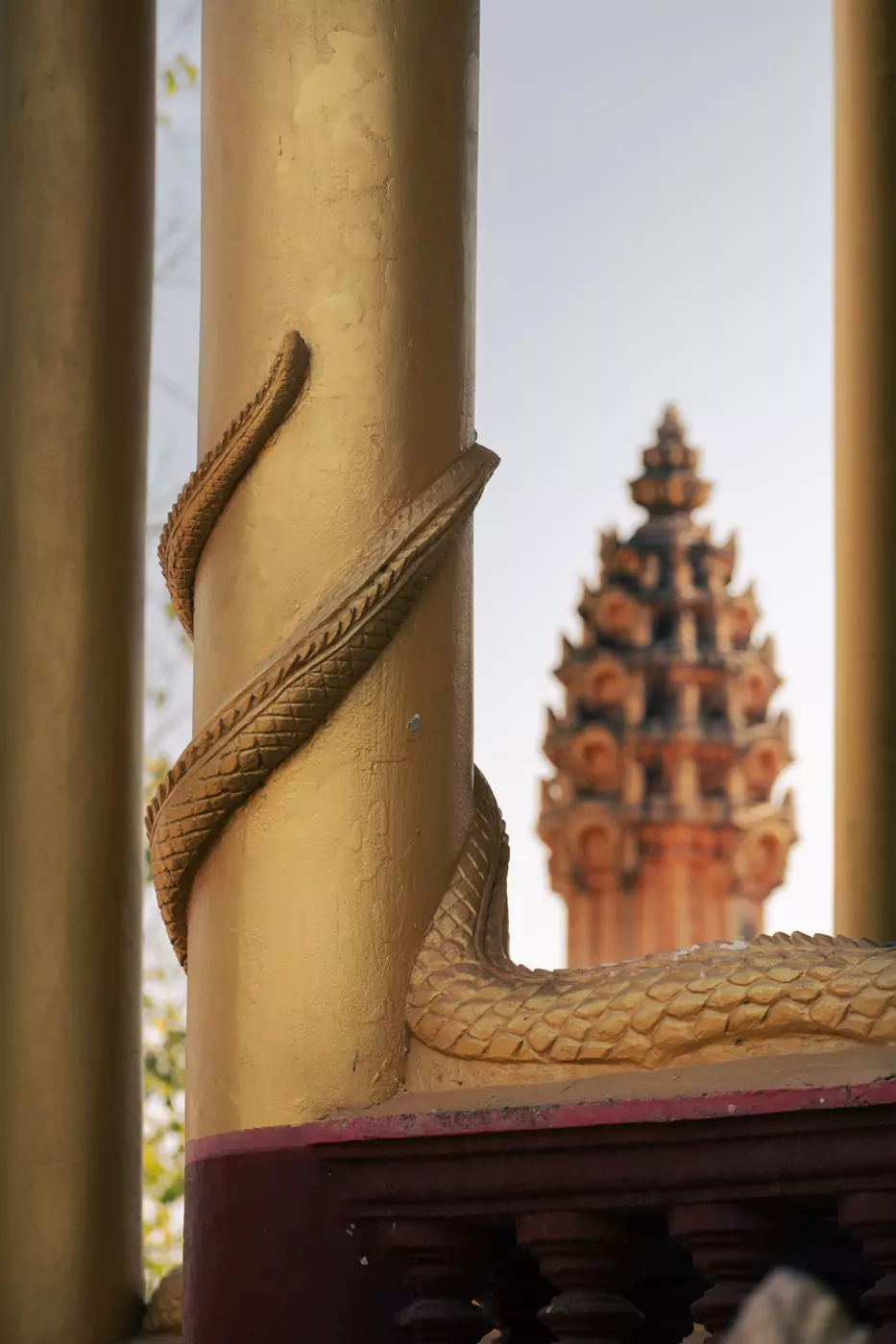 Arquitectura en EK Phnom Pagoda, con una cola de dragón enrollable alrededor de una columna dorada.