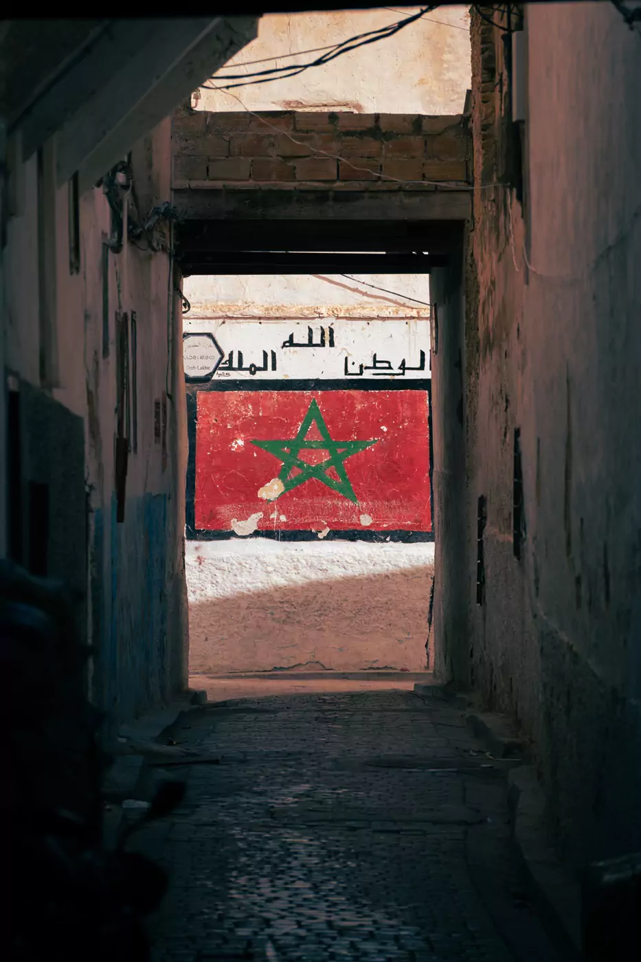 Una bandera marroquí pintada debajo de letras árabes en las paredes de la medina de Fez.