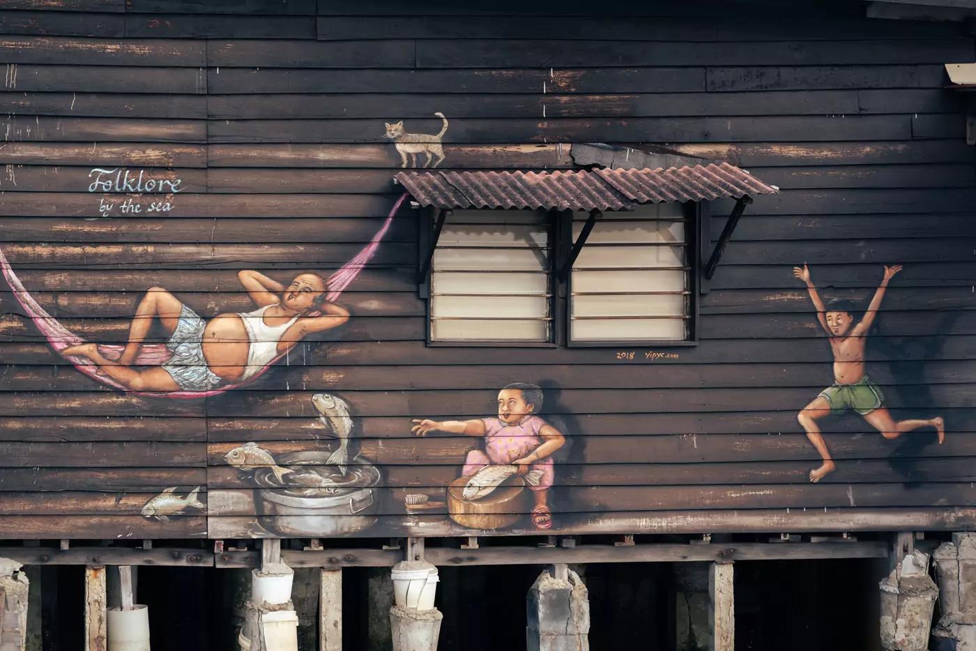 Arte callejero de una familia de pesca al lado de uno de los edificios en el muelle Chew Clan en George Town, Penang.