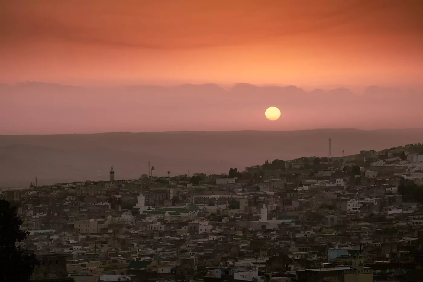Tonos anaranjados intensos de una polvorienta puesta de sol sobre la medina de la ciudad marroquí de Fez.