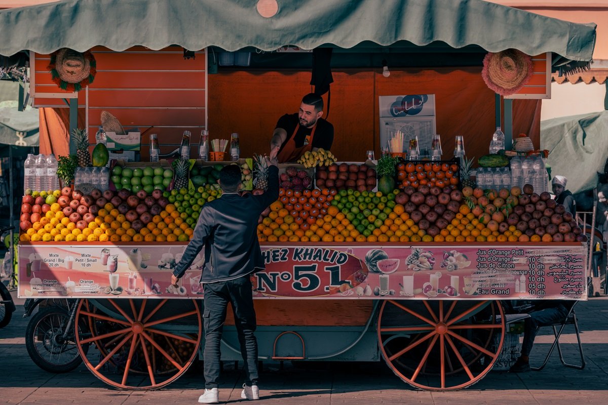 Una persona que compra un poco de fruta de un carrito de frutas y jugo en Jemaa El Fna en Marrakech, una de las hermosas ciudades de Marruecos.